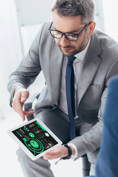 High angle view of handsome businessman in eyeglasses using digital tablet with charts and graphs on screen — Stock Photo