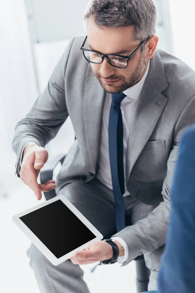 Vista de ángulo alto de hombre de negocios guapo en gafas usando tableta digital con pantalla en blanco - foto de stock