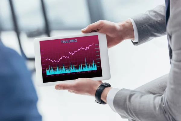 Partial view of businessman holding digital tablet with trading graphs on screen — Stock Photo