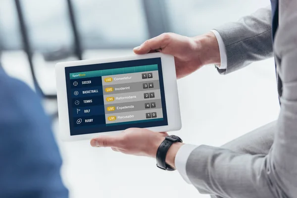 Partial view of businessman holding digital tablet with sport bets app on screen — Stock Photo