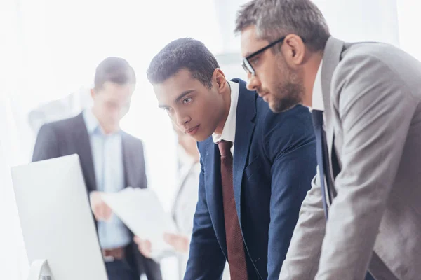 Focused serious businessmen working with desktop computer in office — Stock Photo