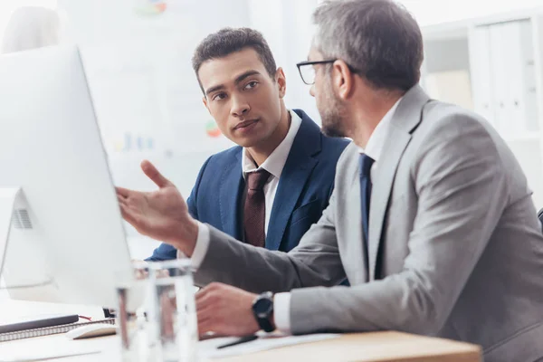 Deux hommes d'affaires professionnels utilisant un ordinateur de bureau et discuter du projet dans le bureau — Photo de stock