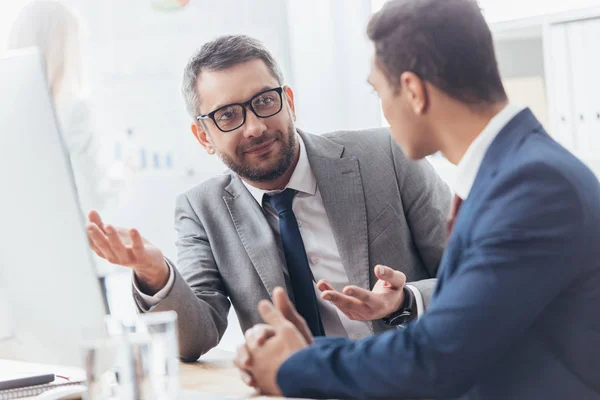 Professional businessmen discussing and using desktop computer at workplace — Stock Photo