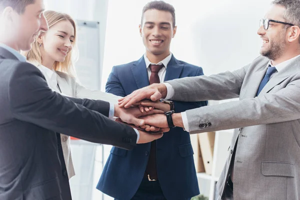 Feliz equipo profesional de negocios apilando manos en la oficina - foto de stock