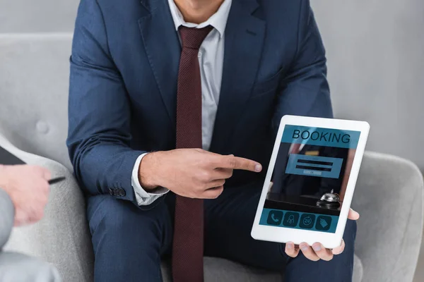 Cropped shot of businessman in formal wear pointing with finger at digital tablet with booking app — Stock Photo