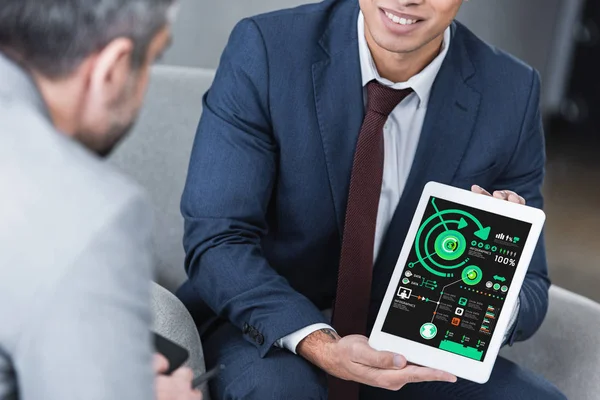 Colpo ritagliato di giovane uomo d'affari che mostra tablet digitale con grafici aziendali al collega — Foto stock