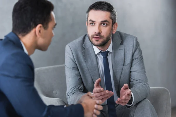 Zwei seriöse Geschäftsleute in Anzügen sitzen zusammen und reden — Stockfoto