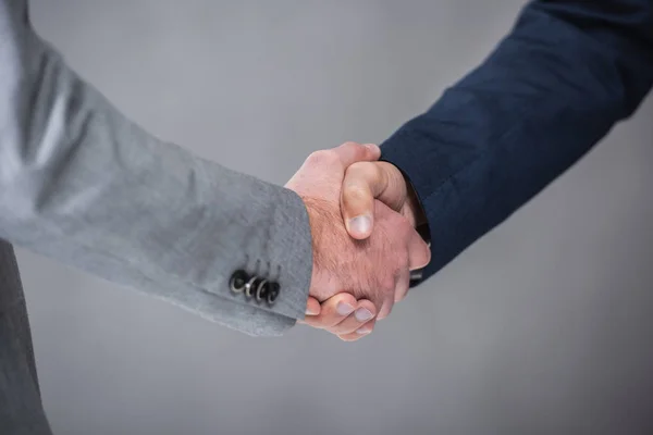 Primo piano vista parziale degli uomini d'affari che stringono la mano sul grigio — Foto stock