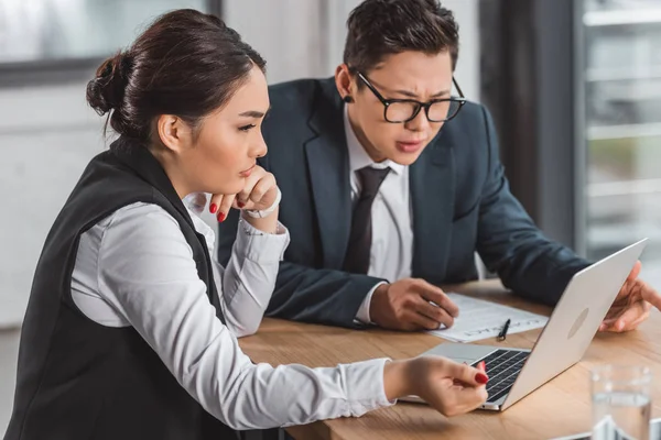 Young concentrated business people using laptop together in office — Stock Photo