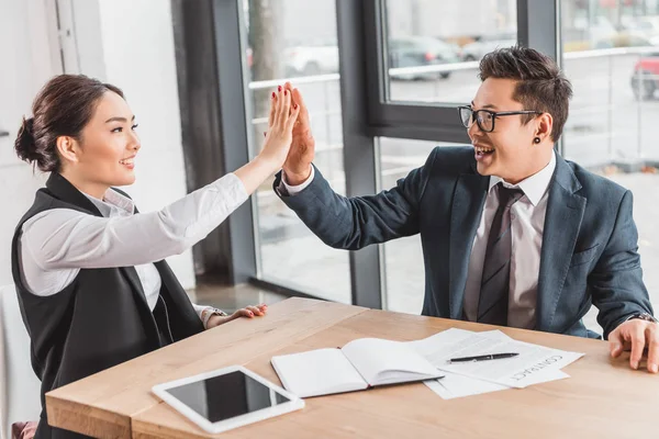 Happy young asian business colleagues giving high five and smiling each other in office — Stock Photo