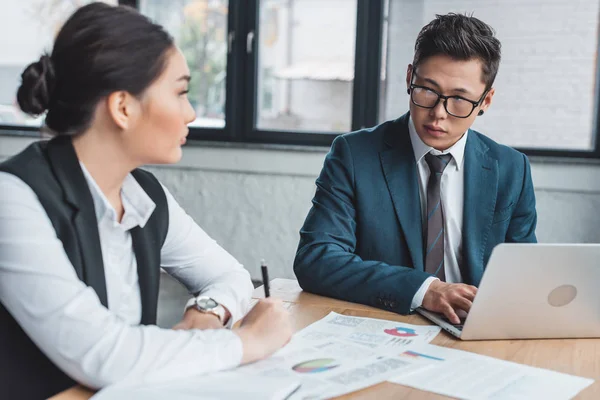 Giovani colleghi di lavoro asiatici che lavorano con documenti e laptop in ufficio — Foto stock