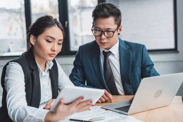 Fokussierte junge asiatische Geschäftsleute, die im Büro mit Laptop und digitalem Tablet arbeiten — Stockfoto