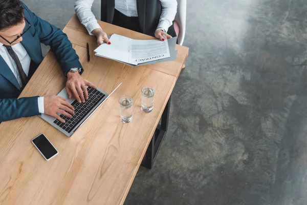 Blickwinkel auf junge Geschäftsleute, die mit Laptop und Vertrag im Büro arbeiten — Stockfoto