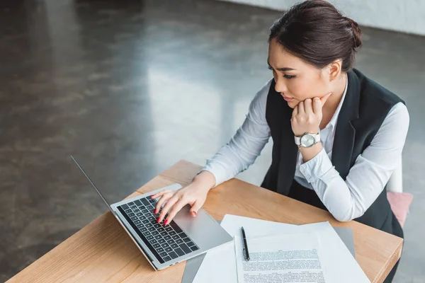 Високий кут зору зосередженої молодої бізнес-леді, використовуючи ноутбук на робочому місці — стокове фото