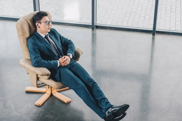 Високий кут зору молодого бізнесмена в костюмі, сидячи в кріслі на робочому місці — стокове фото