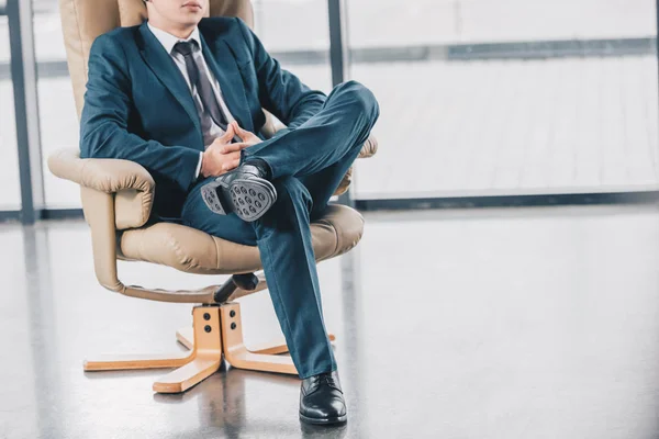 Plan recadré de jeune homme d'affaires en costume assis dans la chaise sur le lieu de travail — Photo de stock