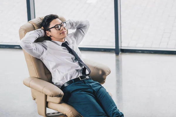 Vue grand angle de jeune asiatique homme d'affaires dans les lunettes de repos dans la chaise — Photo de stock