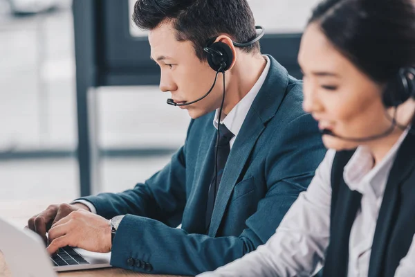 Jóvenes compañeros de trabajo kazakh en auriculares trabajando juntos en el centro de llamadas - foto de stock