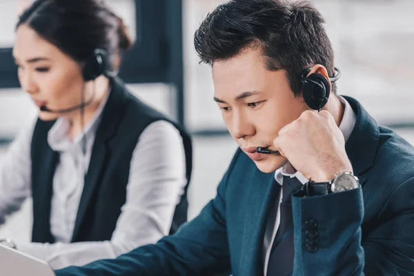 Young call center operators in headsets working in office — Stock Photo