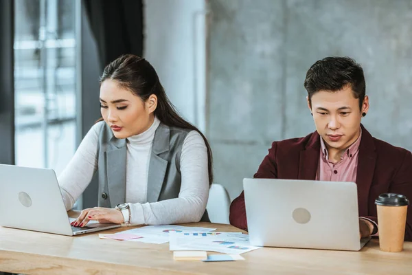 Jeunes gens d'affaires kazakh ciblés utilisant des ordinateurs portables sur le lieu de travail — Photo de stock