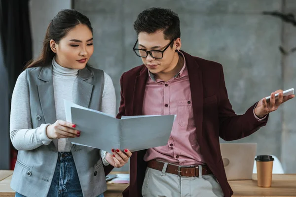 Young asian business colleagues looking at folder with papers in office — Stock Photo