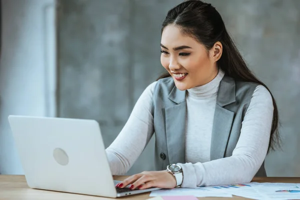 Bela sorridente jovem empresária usando laptop no escritório — Fotografia de Stock