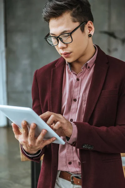Beau jeune homme d'affaires concentré dans les lunettes en utilisant une tablette numérique au bureau — Photo de stock