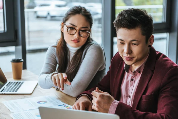 Jeunes asiatiques collègues d'affaires regardant ordinateur portable et de travailler ensemble dans le bureau — Photo de stock