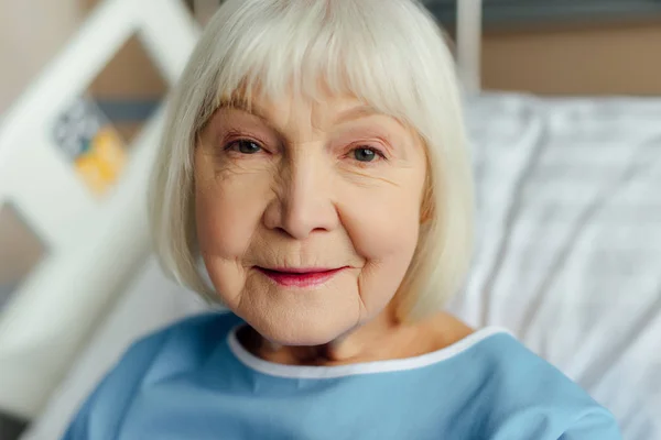 Retrato de mulher sênior sorridente com cabelos grisalhos olhando para a câmera no hospital — Fotografia de Stock