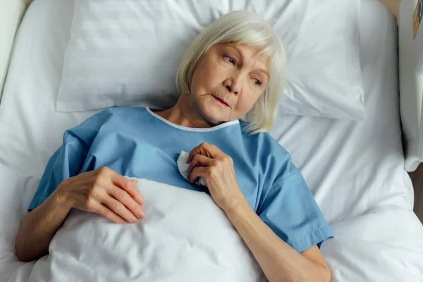 Sad lonely senior woman lying in hospital bed — Stock Photo