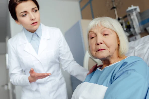 Sconvolto medico femminile consolante triste donna anziana sdraiata nel letto d'ospedale — Foto stock