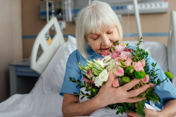 Вибірковий фокус на відновленні старшої жінки на ліжку з квітами в лікарні — стокове фото