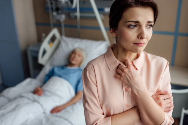 Selective focus of worried daughter with sick mother in bed on background in hospital with copy space — Stock Photo