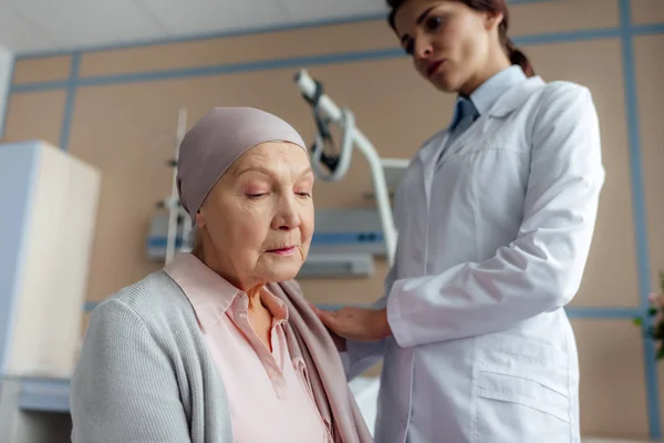 Medico donna consolante triste donna anziana in fazzoletto con cancro in ospedale — Foto stock