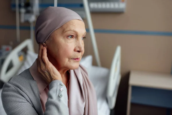 Засмучена старша жінка з раком сидить на ліжку в лікарні — стокове фото