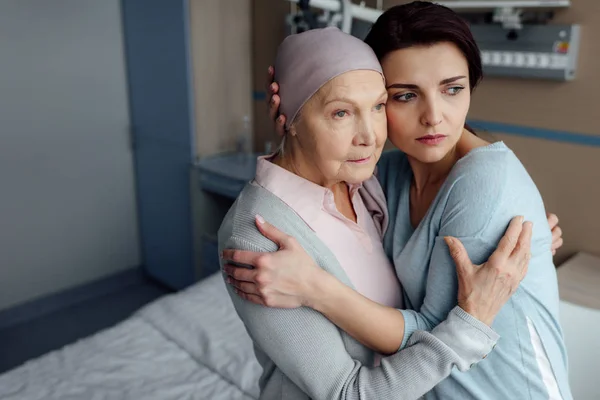 Sad daughter embracing sick senior mother with cancer in hospital — Stock Photo