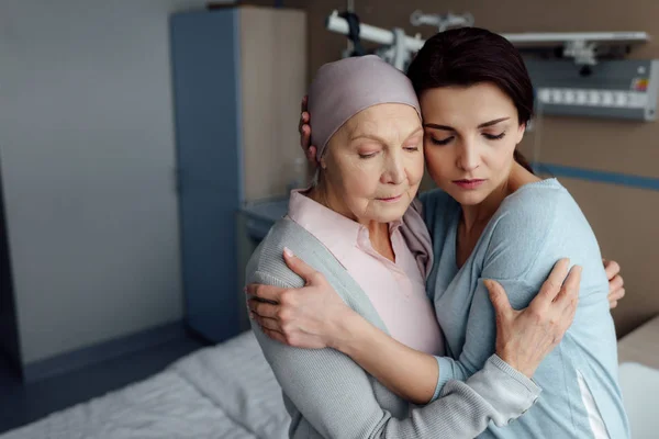 Sconvolto figlia abbracciando malato madre anziana con il cancro in ospedale — Foto stock