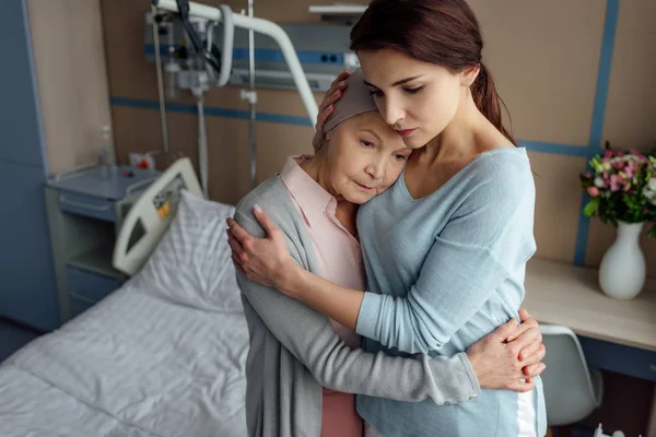 Filha triste abraçando doente mãe sênior com câncer no hospital — Fotografia de Stock