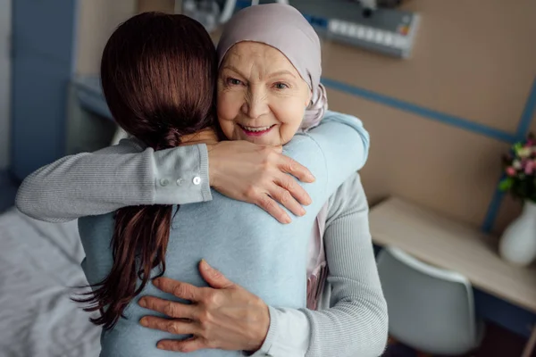 Heureuse femme âgée en mouchoir embrassant fille à l'hôpital — Photo de stock