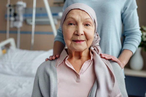 Donna anziana in fazzoletto con figlia sullo sfondo in ospedale — Foto stock