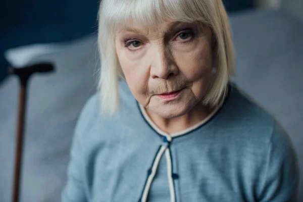 Ritratto di donna anziana triste con i capelli grigi che guarda la macchina fotografica a casa — Foto stock