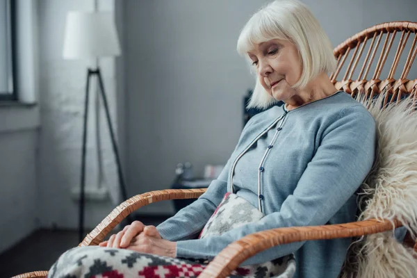 Seniorin sitzt zu Hause im Weidenschaukelstuhl — Stockfoto