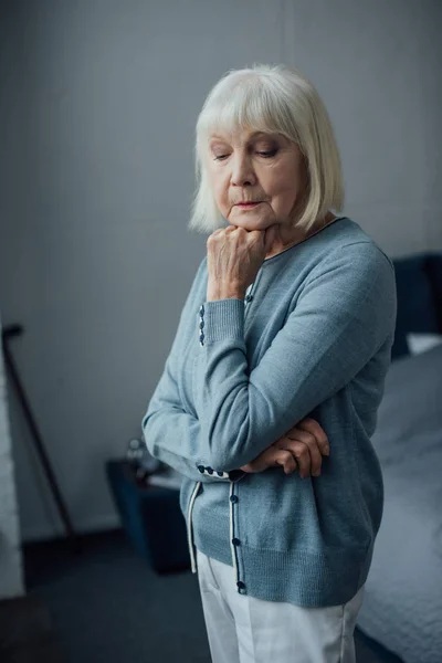 Pensive senior woman in casual sweater propping chin with hand at home — Stock Photo