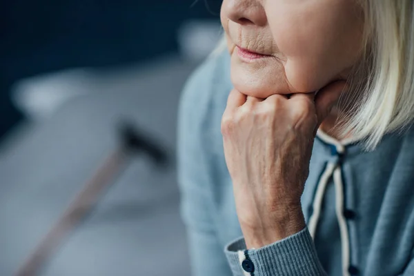 Ausgeschnittene Ansicht einer Seniorin, die zu Hause mit der Hand das Kinn stützt — Stockfoto