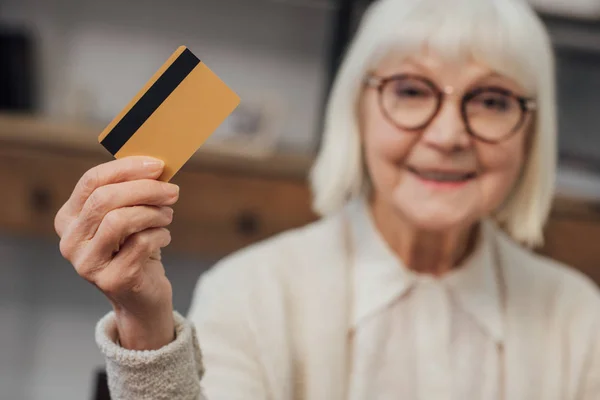 Foco seletivo do cartão de crédito na mão de mulher smiling sênior — Fotografia de Stock