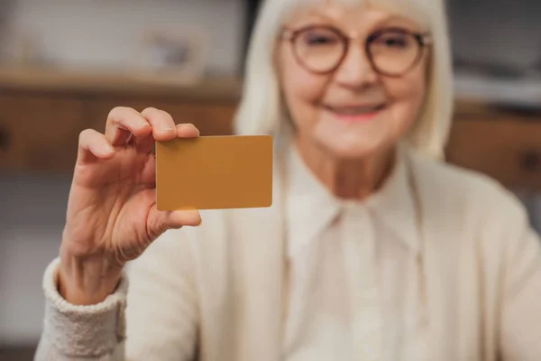 Foco seletivo de cartão de crédito na mão de mulher sênior — Fotografia de Stock