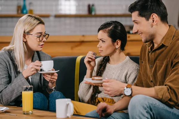 Woman in glasses chatting with friends while holding cup  in cafe — Stock Photo