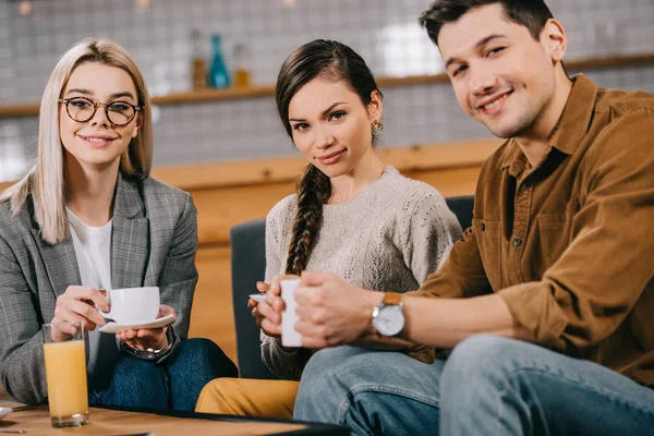 Happy group of friends holding cups in cafe — Stock Photo