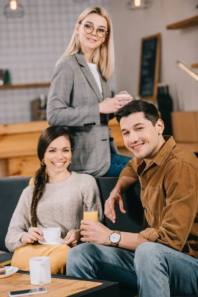 Amigos alegres sorrindo e segurando copos no café — Fotografia de Stock