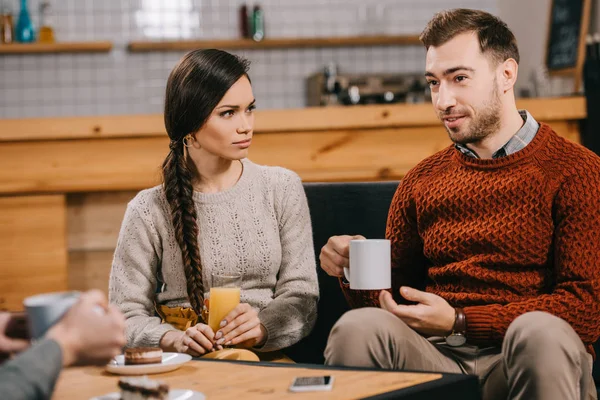 Selective focus of friends chatting in cafe while holding drinks — Stock Photo